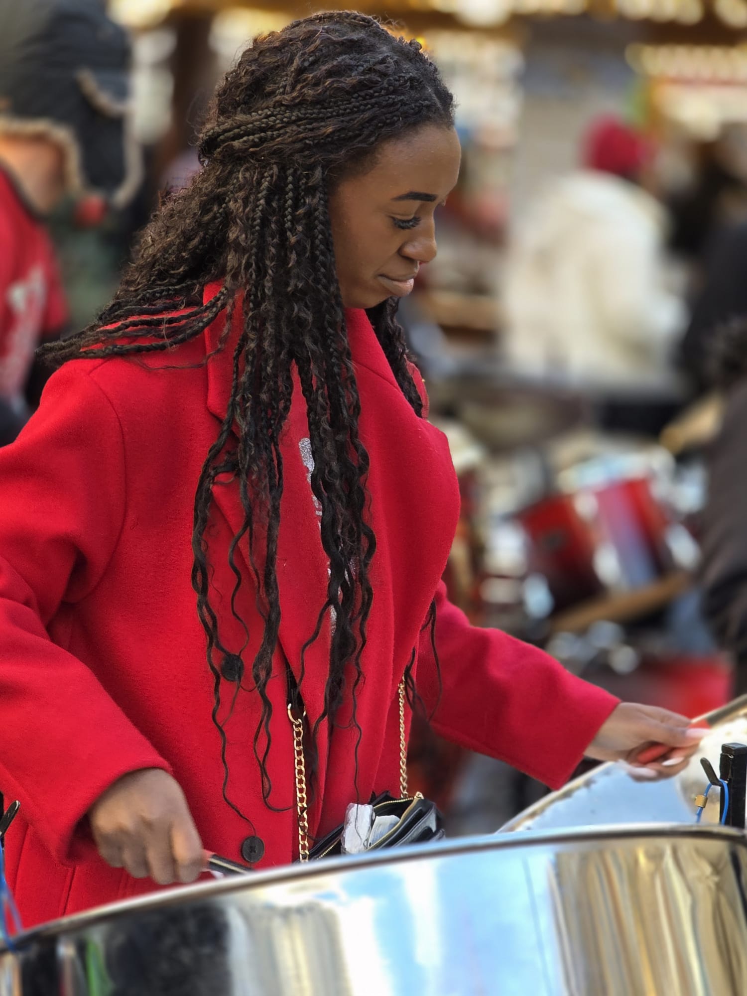 Black girl in red coat plays with a steel band - RASPO Calypso & Carols 2025 image by Julia Brazil